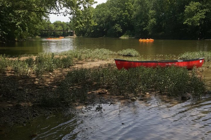 a boat floating along a river next to a body of water