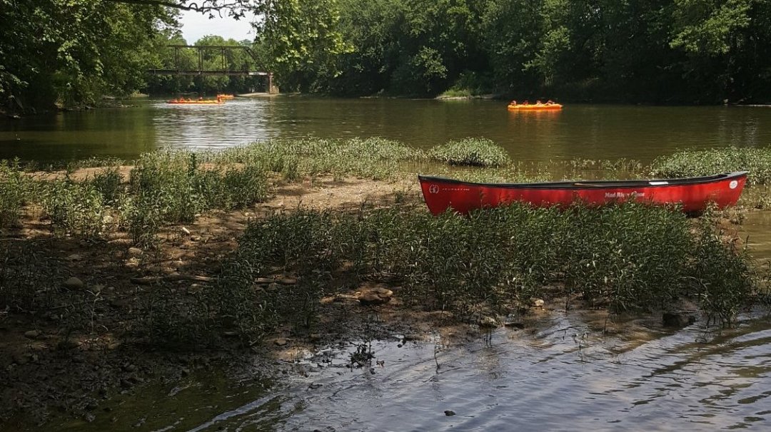 a boat floating along a river next to a body of water