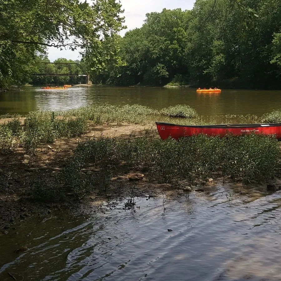 a boat floating along a river next to a body of water